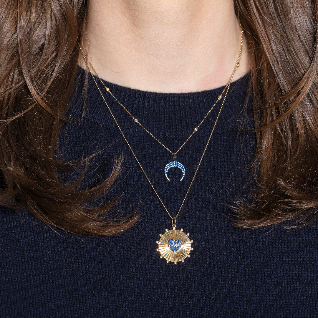 Two necklaces with heart-shaped pendants on a dark blue sweater