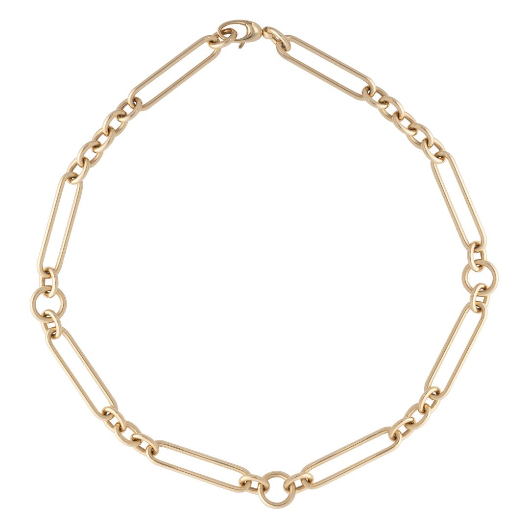A gold chunky mixed link chain necklace laid out on a plain surface.