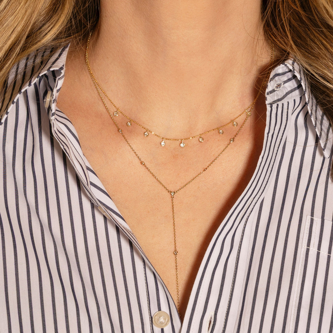 Gold necklace worn by a person with a striped shirt