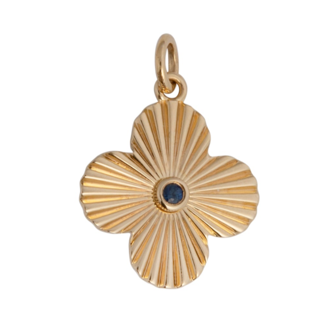 A gold pendant featuring a clover-shaped design with a blue sapphire center stone.