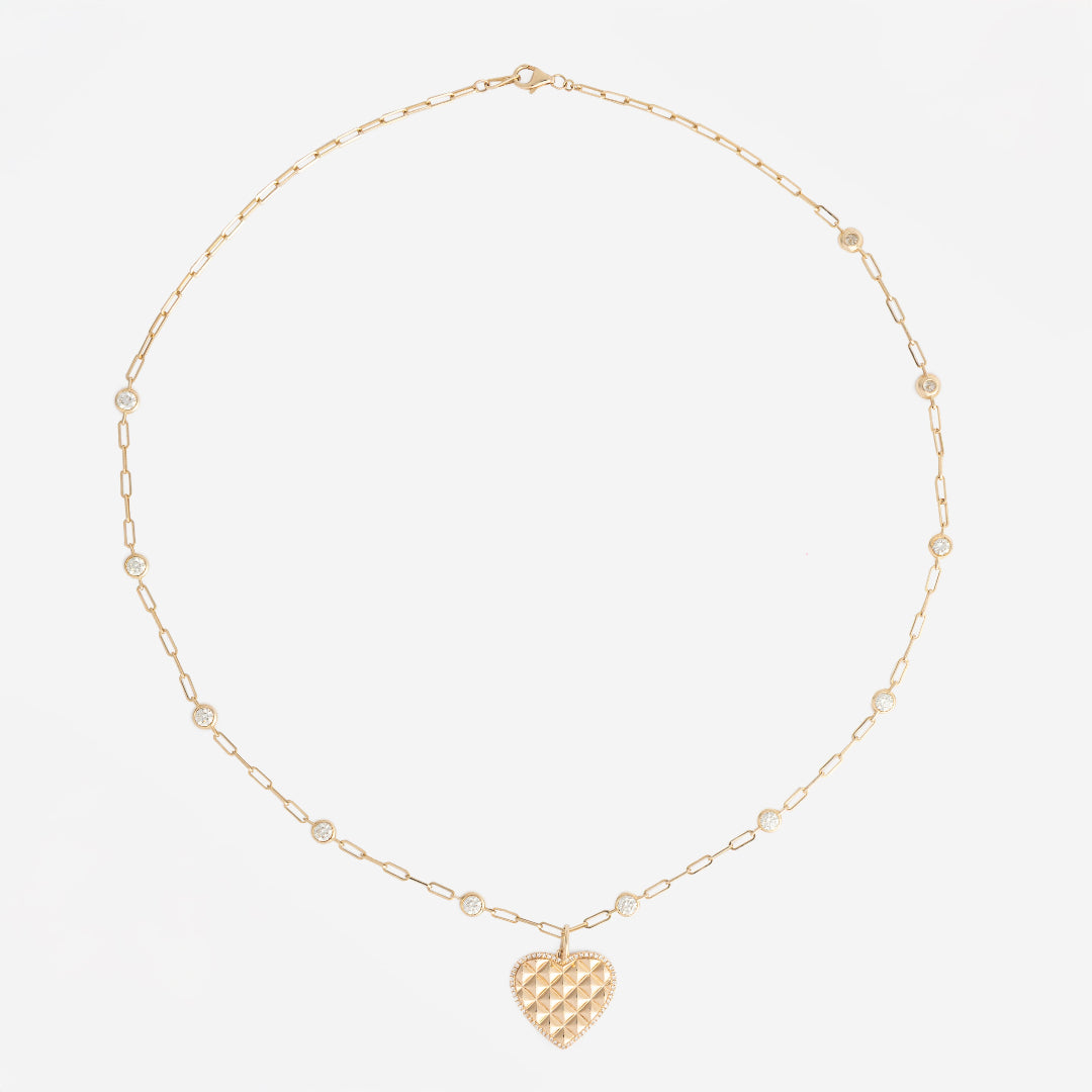 Gold diamond station necklace with a heart pendant on a white background.