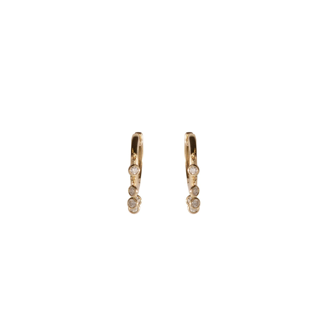A pair of gold hoops with dangling bezel set diamonds on a white background.