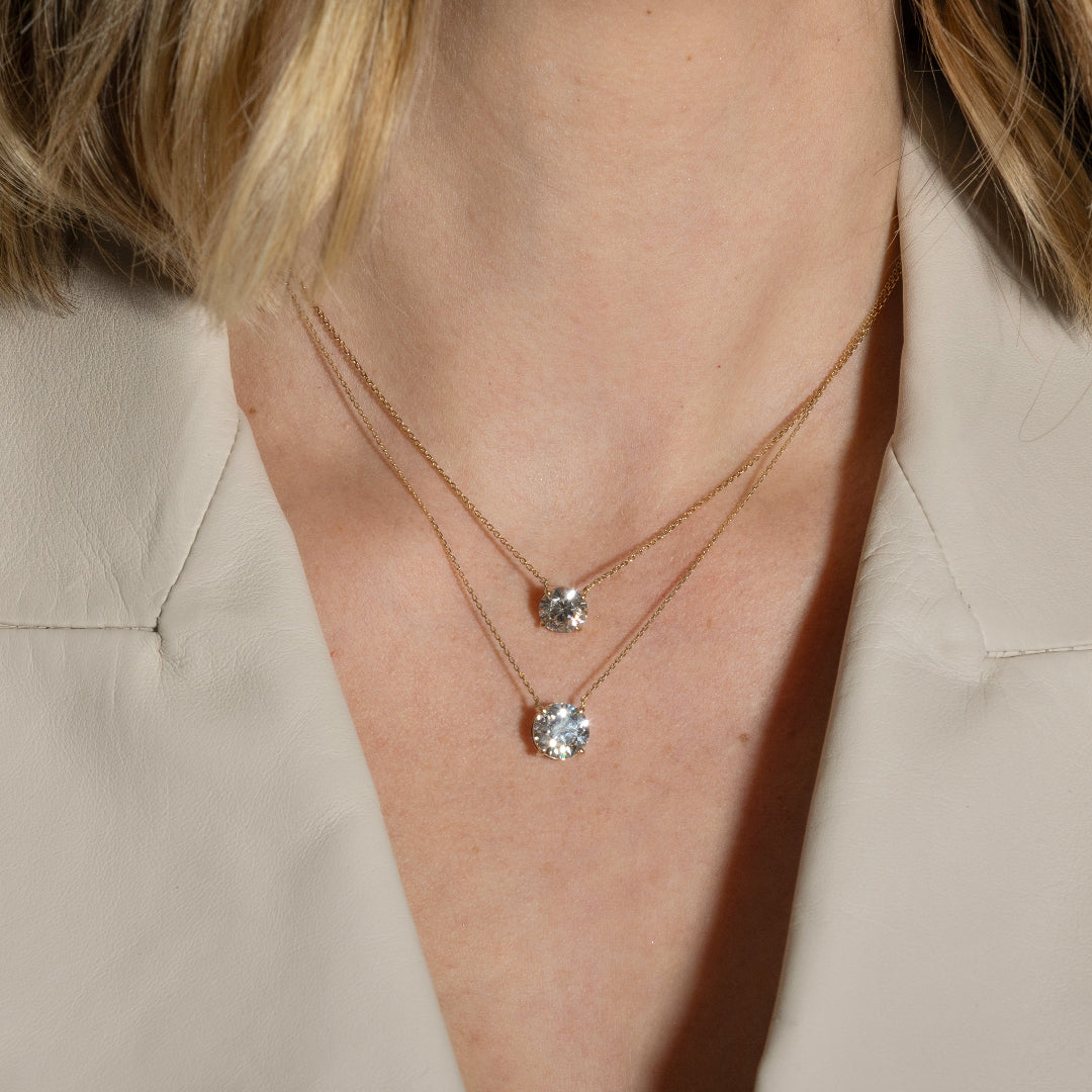 Close-up of a person wearing two necklaces with solitare lab-grown diamond pendants.