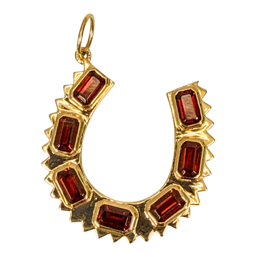 14k gold pendant with garnets on a white background.