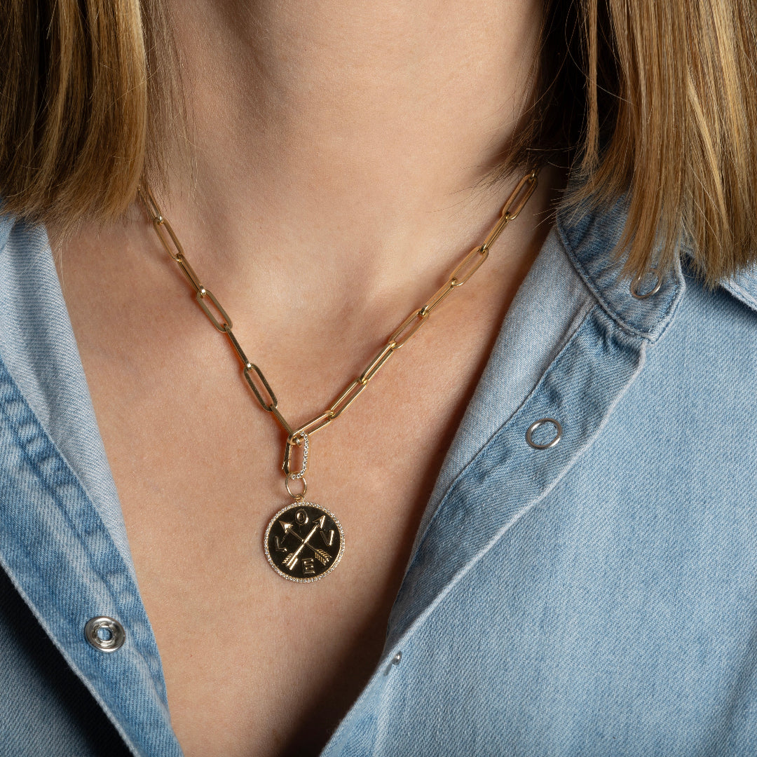 A person wearing a paperclip chain with a gold pendant attached.