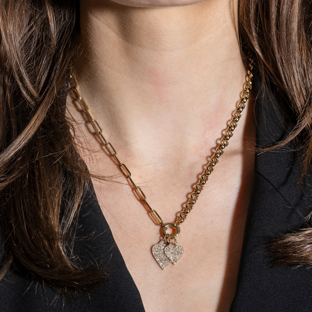 Gold chain necklace with heart-shaped pendant worn by a person