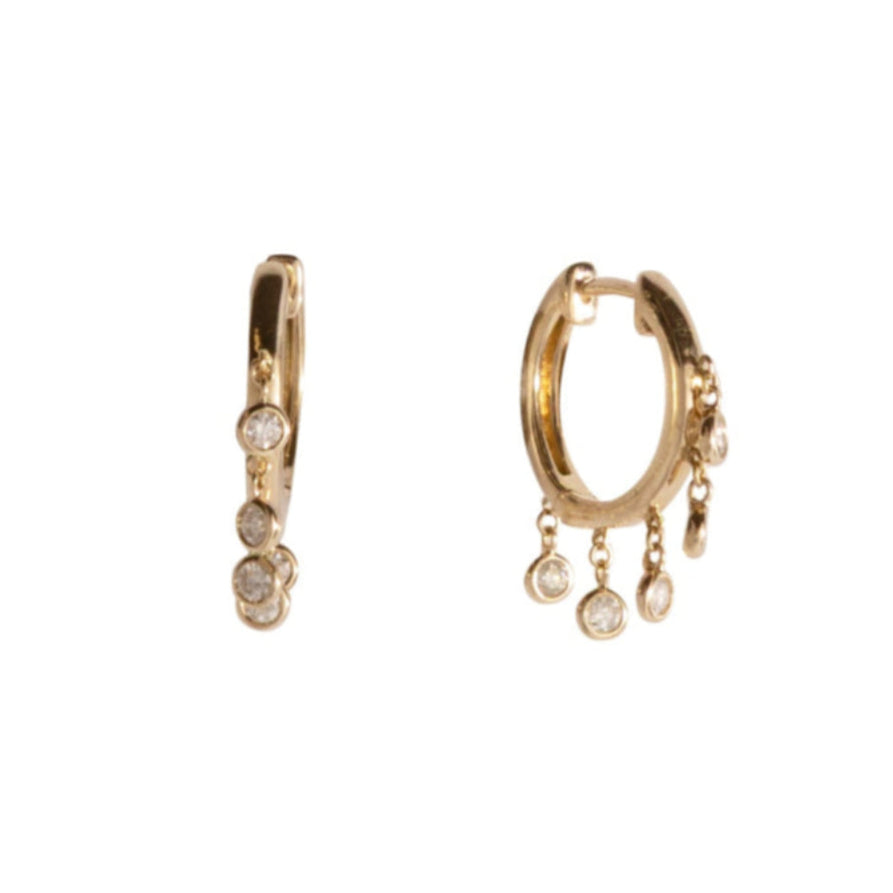 A pair of gold hoops with dangling bezel set diamonds on a white background.