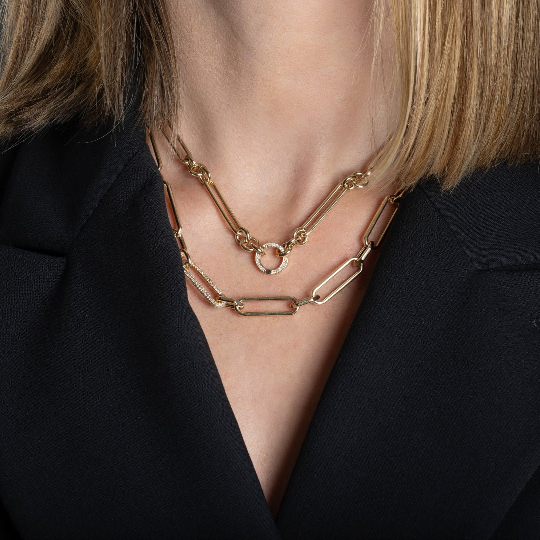 A person in a black blazer wearing a 14k gold necklace with a double-sided diamond enhancer, featuring oval and round link chains with a mixed link gold chain.