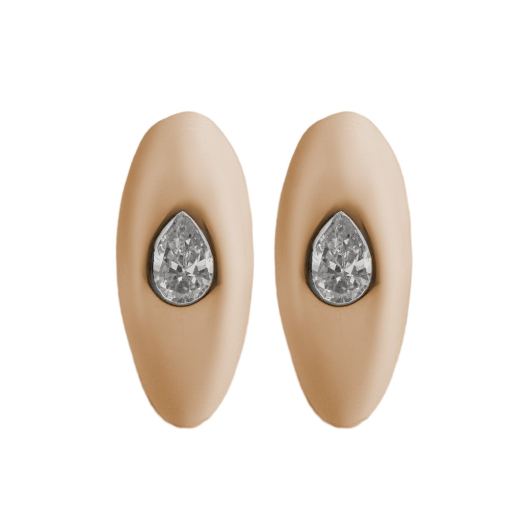 A pair of pear diamond huggie earrings in 14k gold, with a pear shaped diamond in each earring.