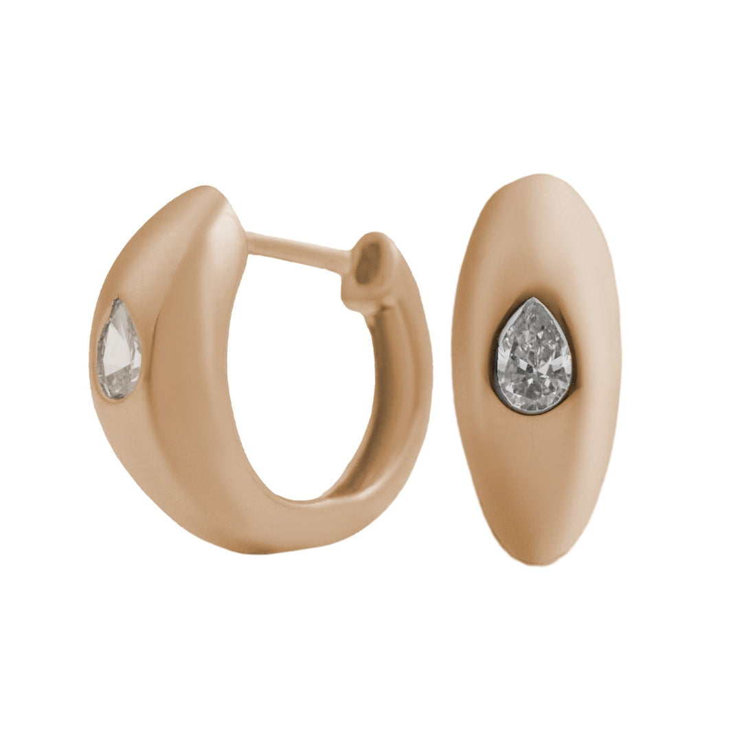 A pair of pear diamond huggie earrings in 14k gold with a single pear shaped, one is turned sideways to showcase how they close.