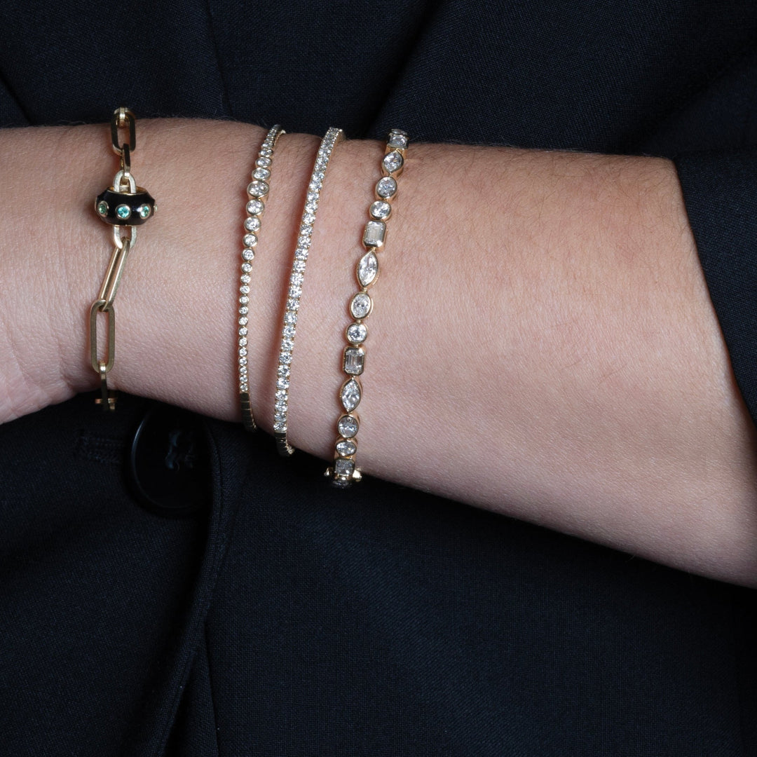 Close-up of a wrist wearing multiple diamond bracelets on a dark background