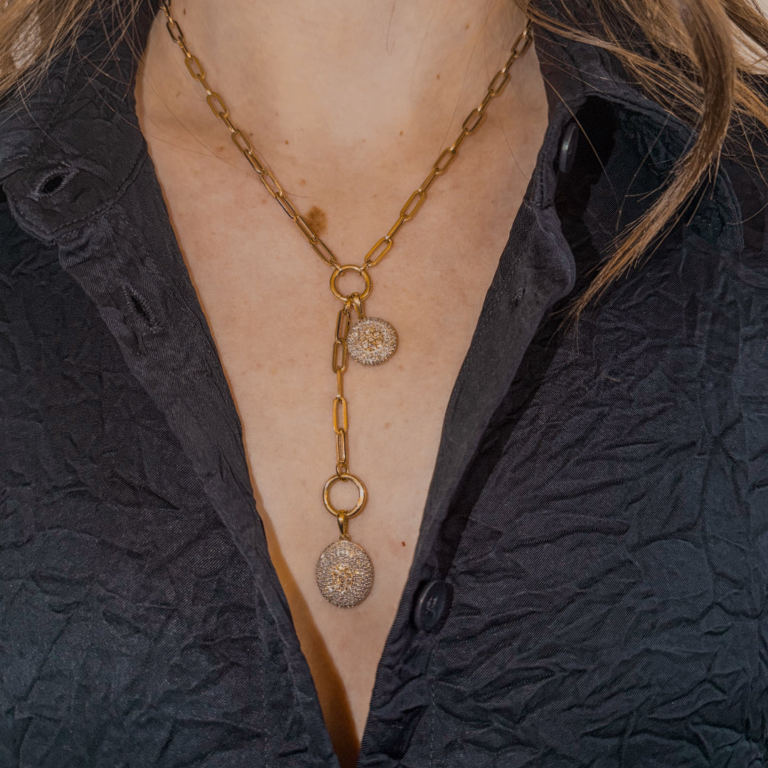 14k gold chain necklace with two pavé diamond pendants worn by a person in a dark textured garment.