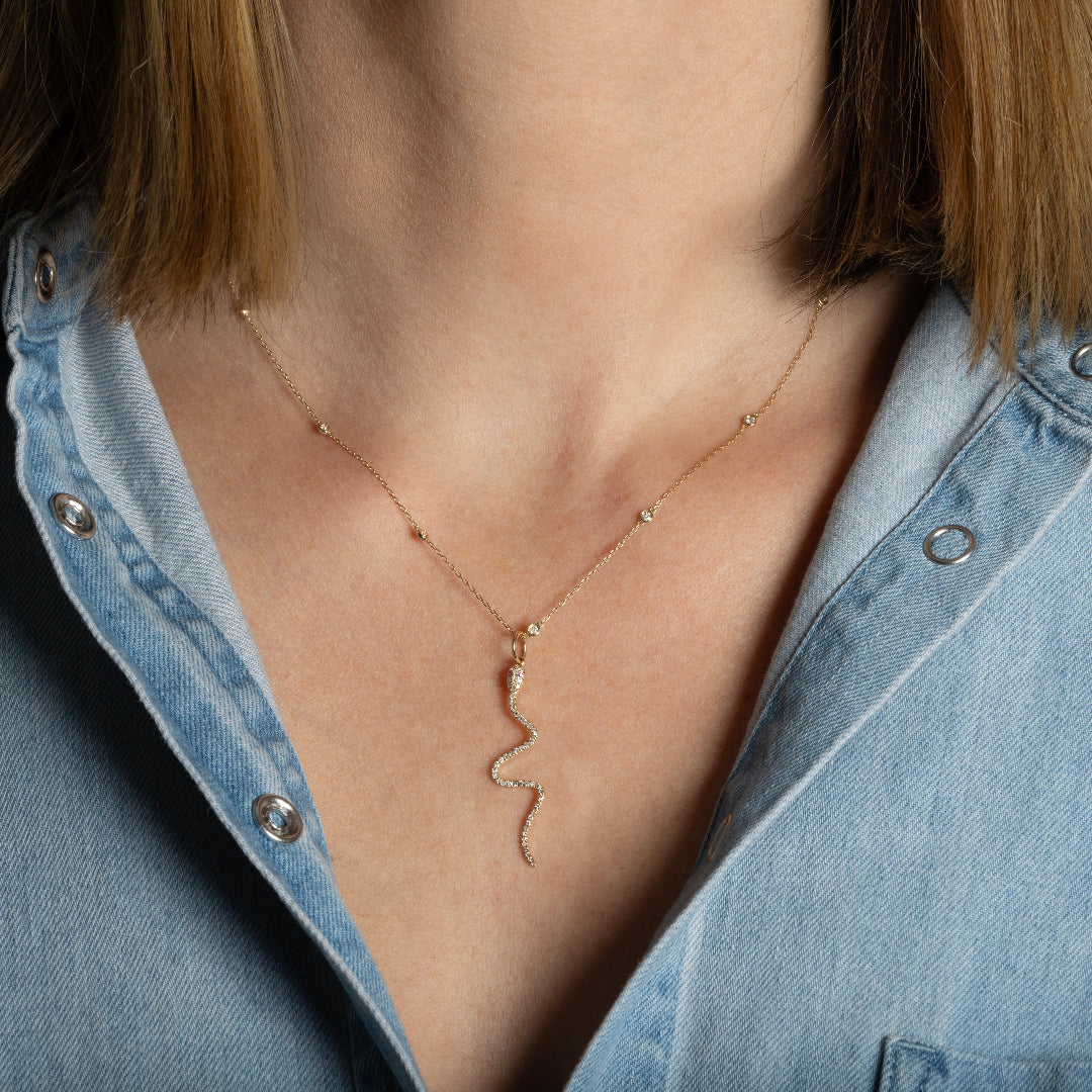 A person wearing a mini diamond station chain with a diamond serpent pendant.