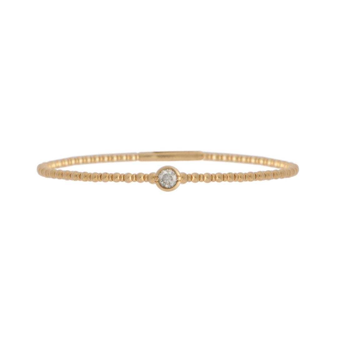 Gold bracelet with a single station diamond on a white background