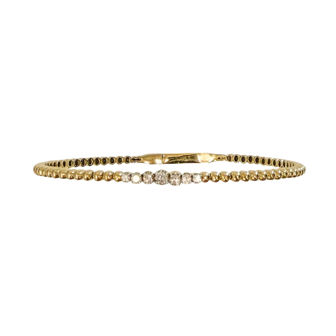 14k gold flexible bracelet with diamonds in the center on a white background.