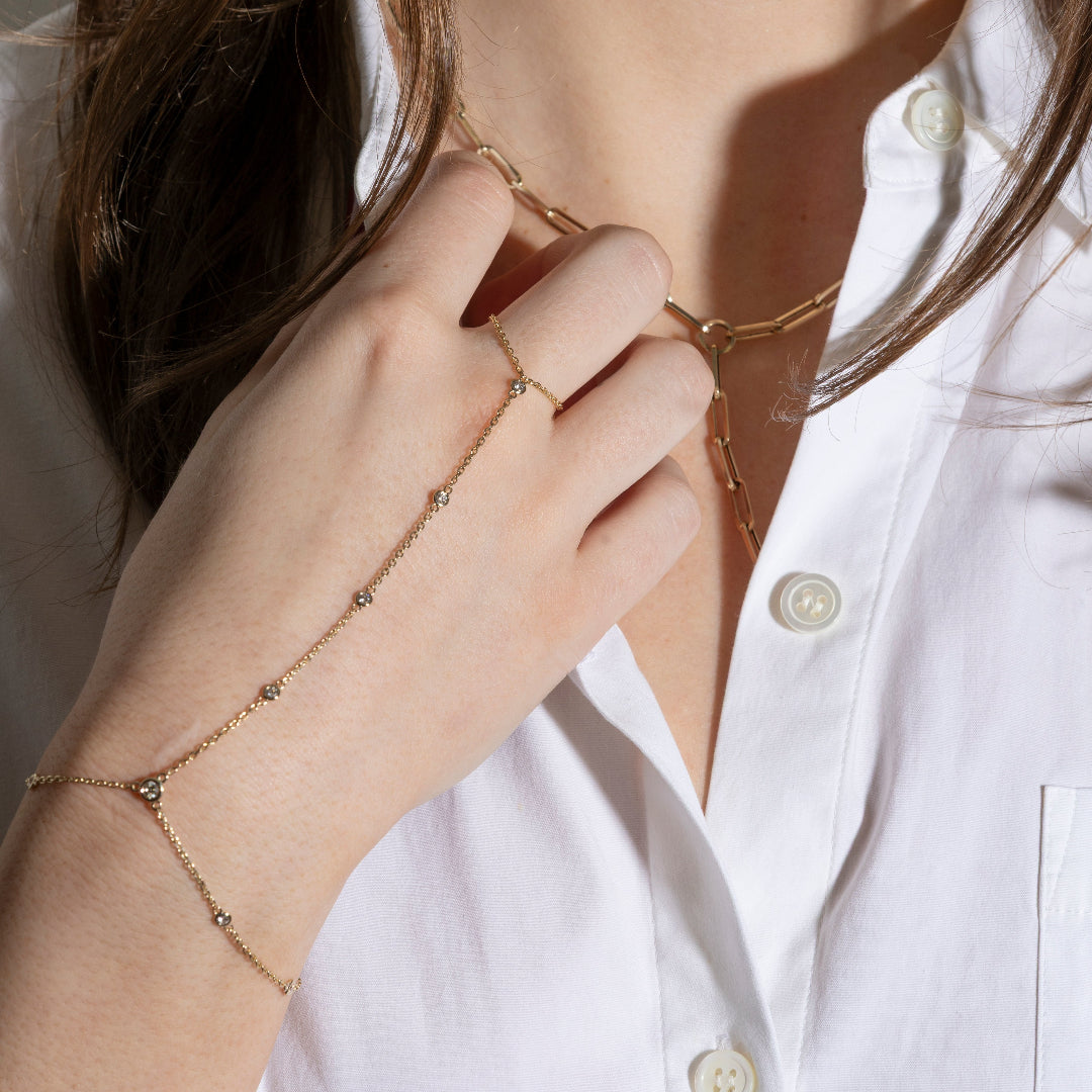 Gold bracelet on a wrist with a white shirt in the background
