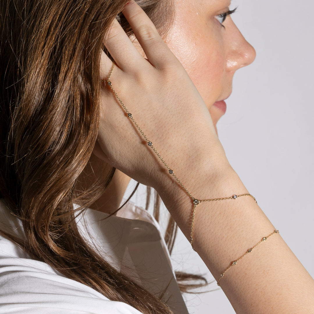 Woman wearing a delicate gold diamond bracelet on a plain background