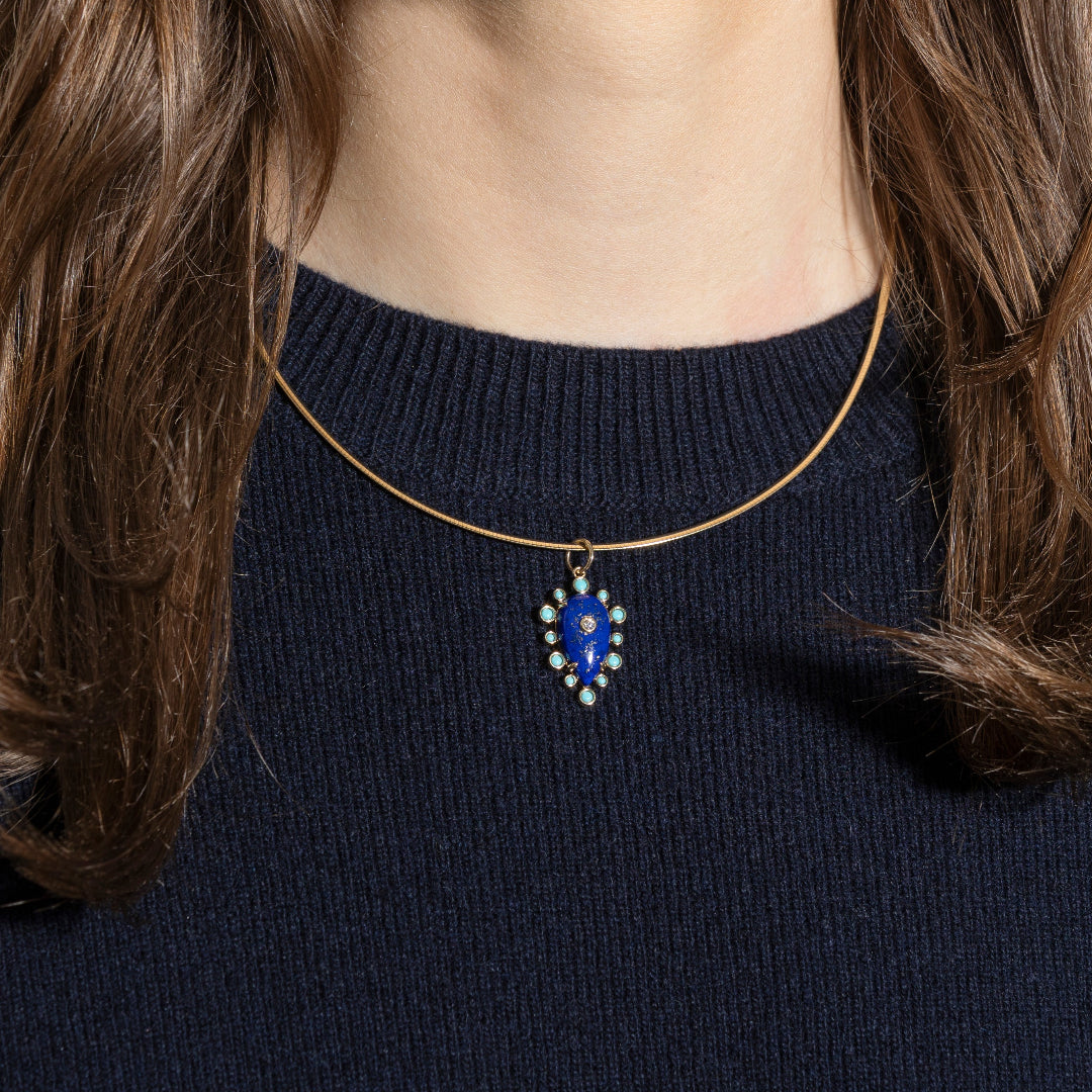 Close-up of a necklace with a blue pendant worn by a person against a dark background