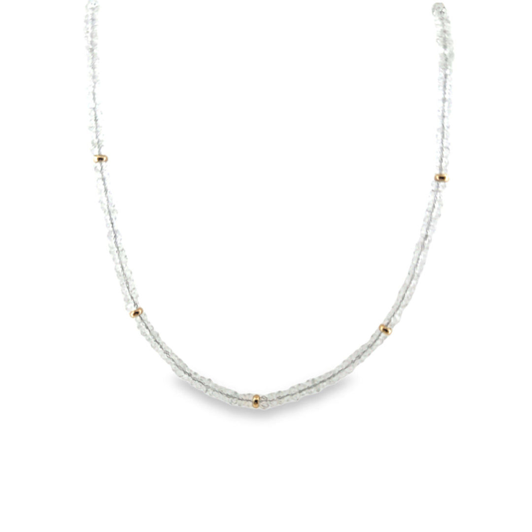 A close-up of a white topaz bead necklace with 14k gold beads on a white background.