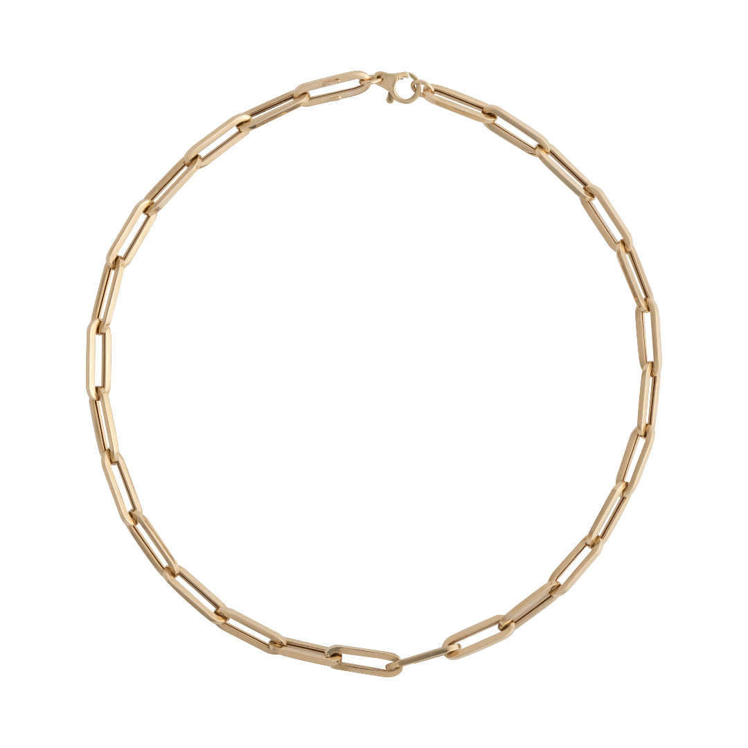 A gold paperclip chain necklace laid out on a plain background.