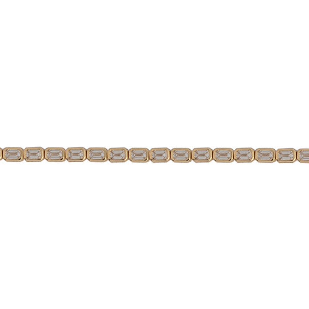 A close up of an emerald shaped tennis bracelet with an east-west orientation, set in 14k gold.