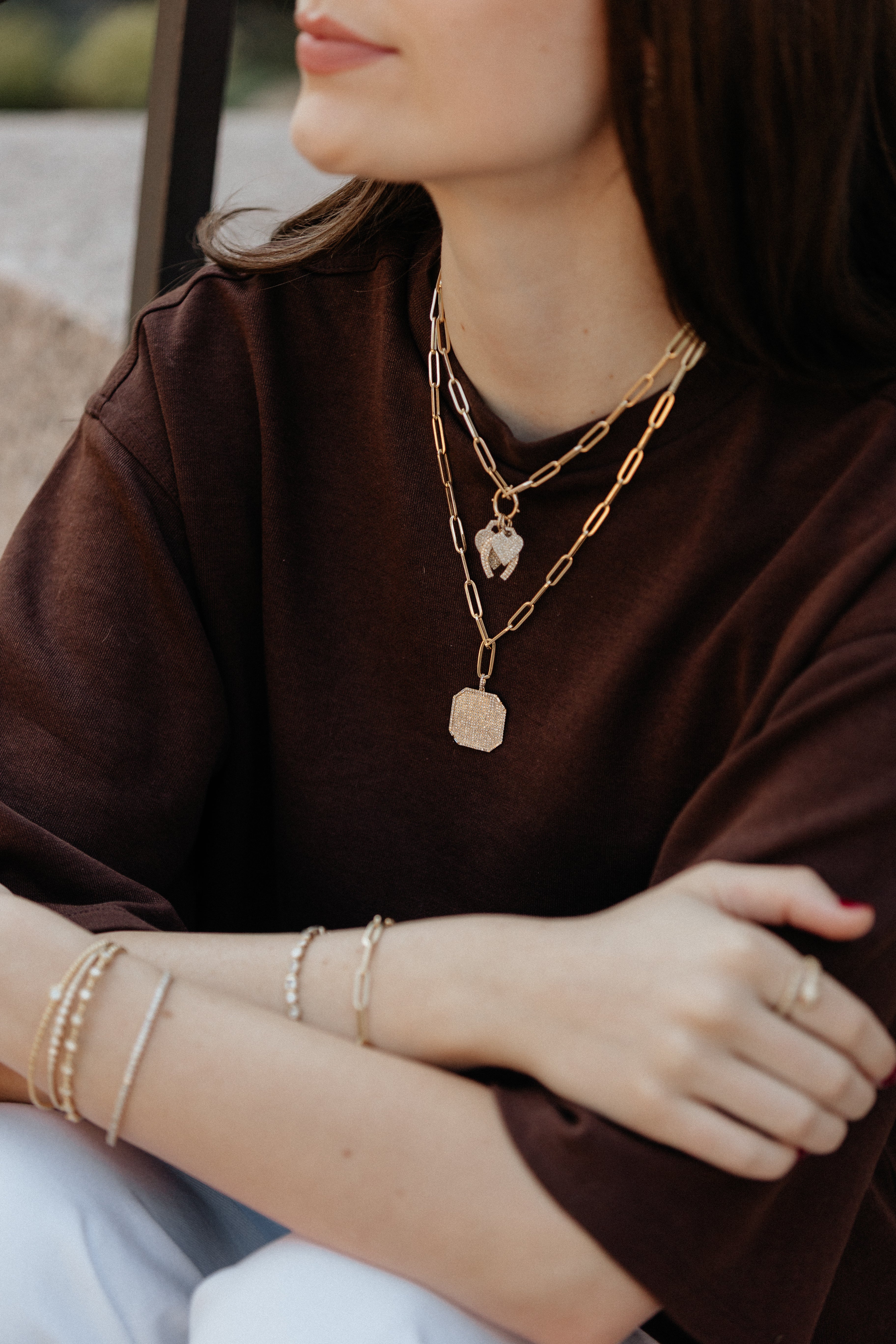 Person wearing gold jewelry including necklaces, bracelets, and rings.