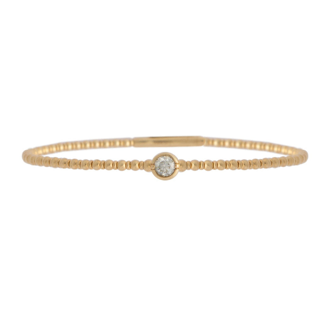 Gold bracelet with a single station diamond on a white background