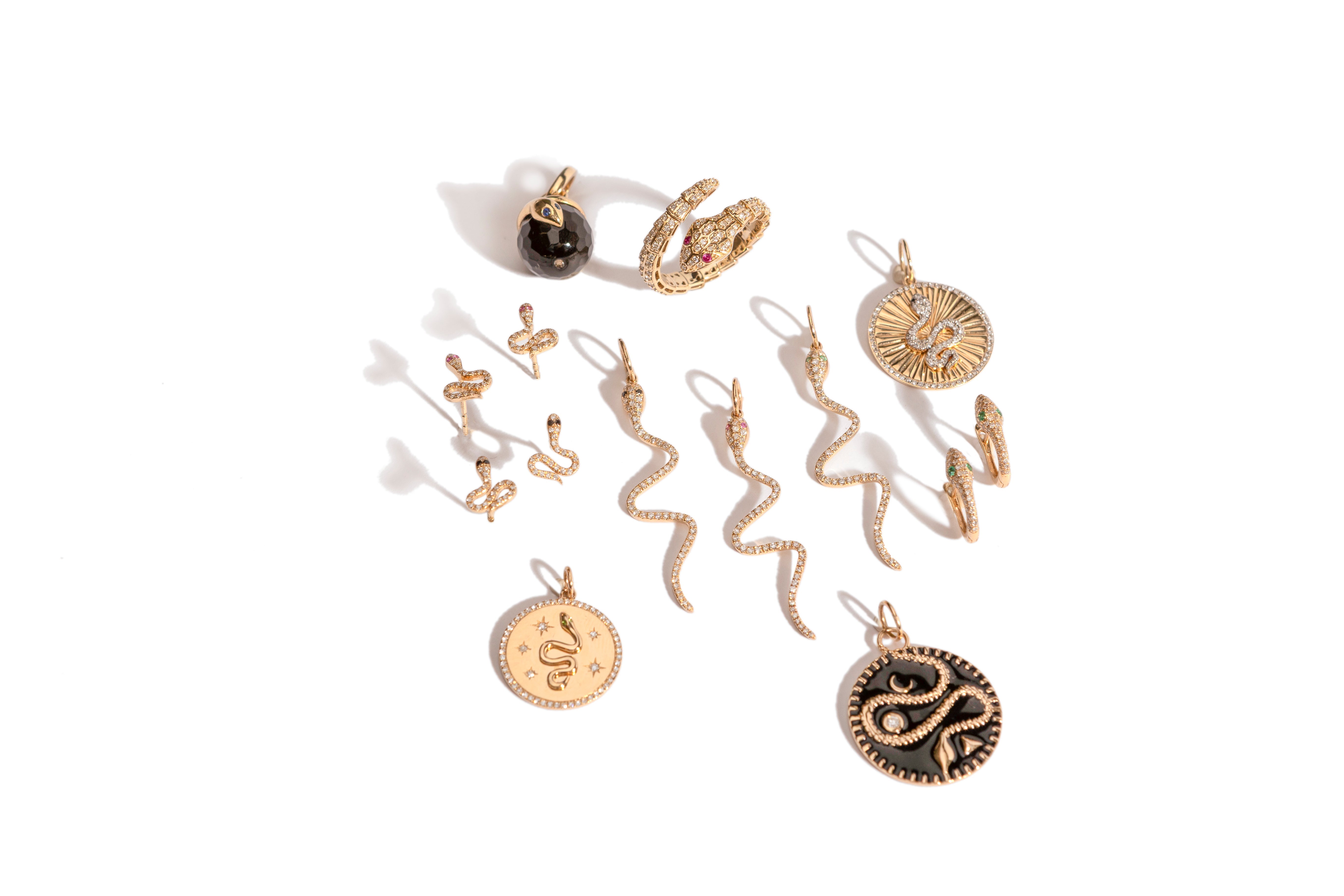 A collection of serpent jewelry items, all gold with diamonds, on a white background.