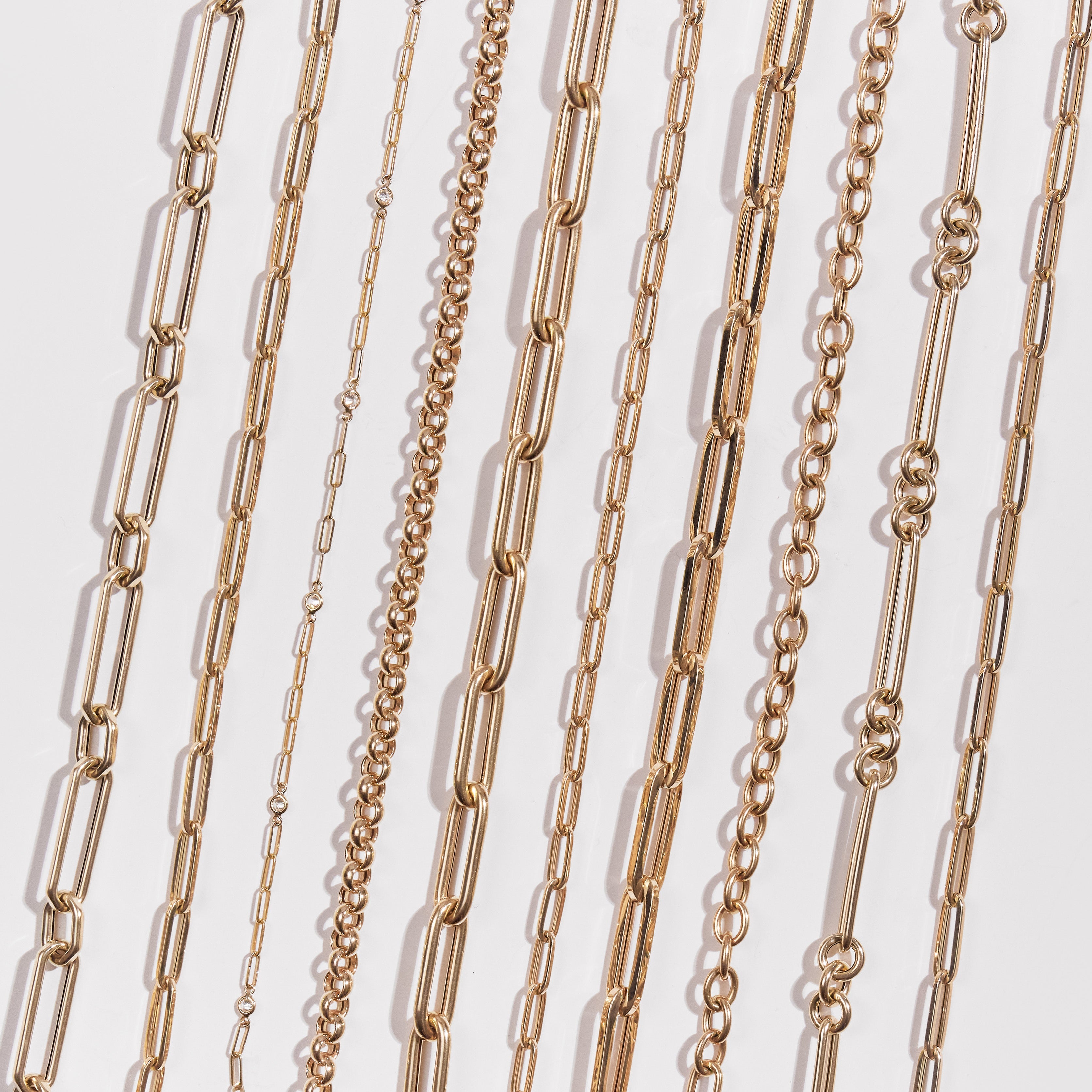 A collection of numerous gold chains against a white background.