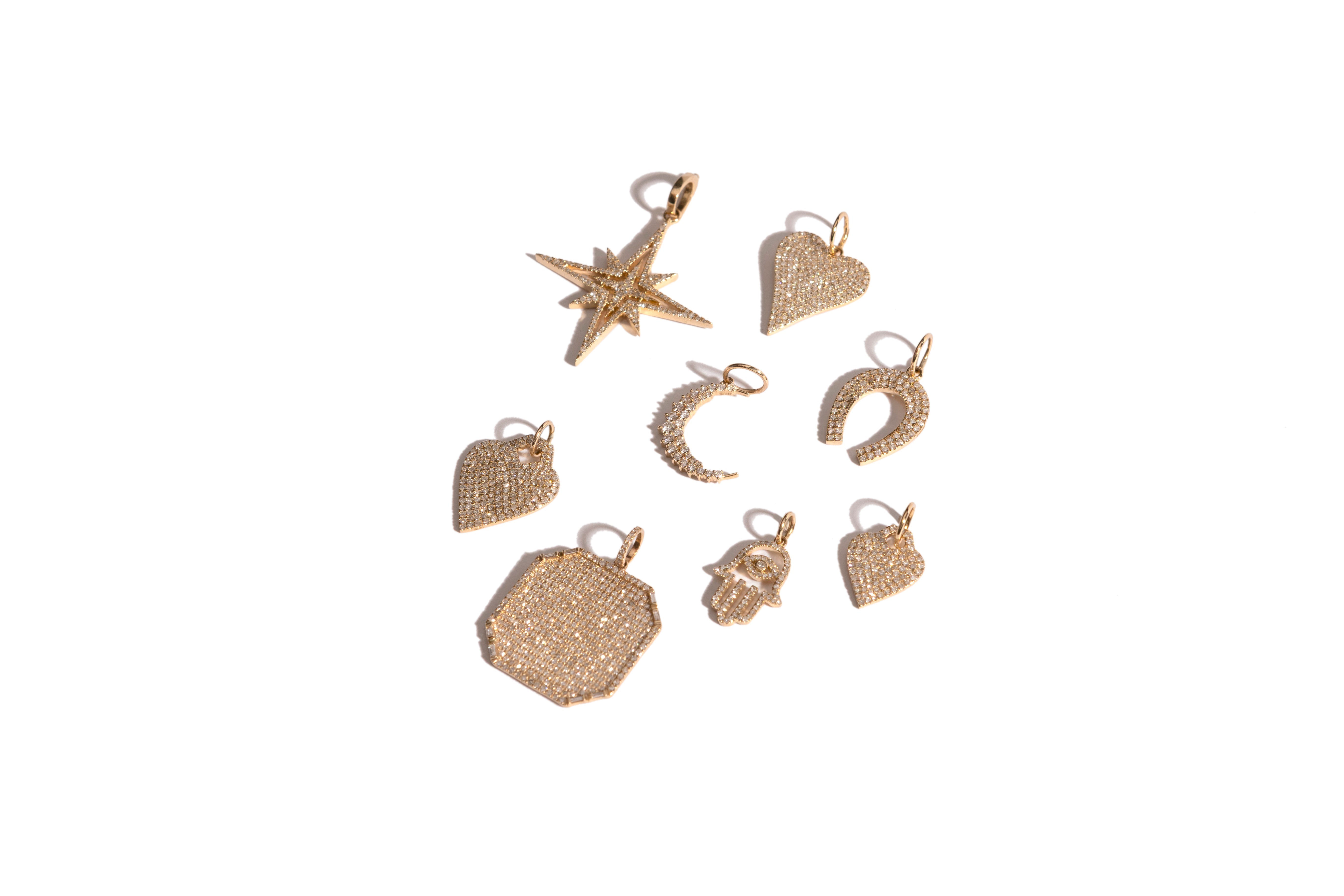 A collection of gold and diamond pavé pendants on a white background.