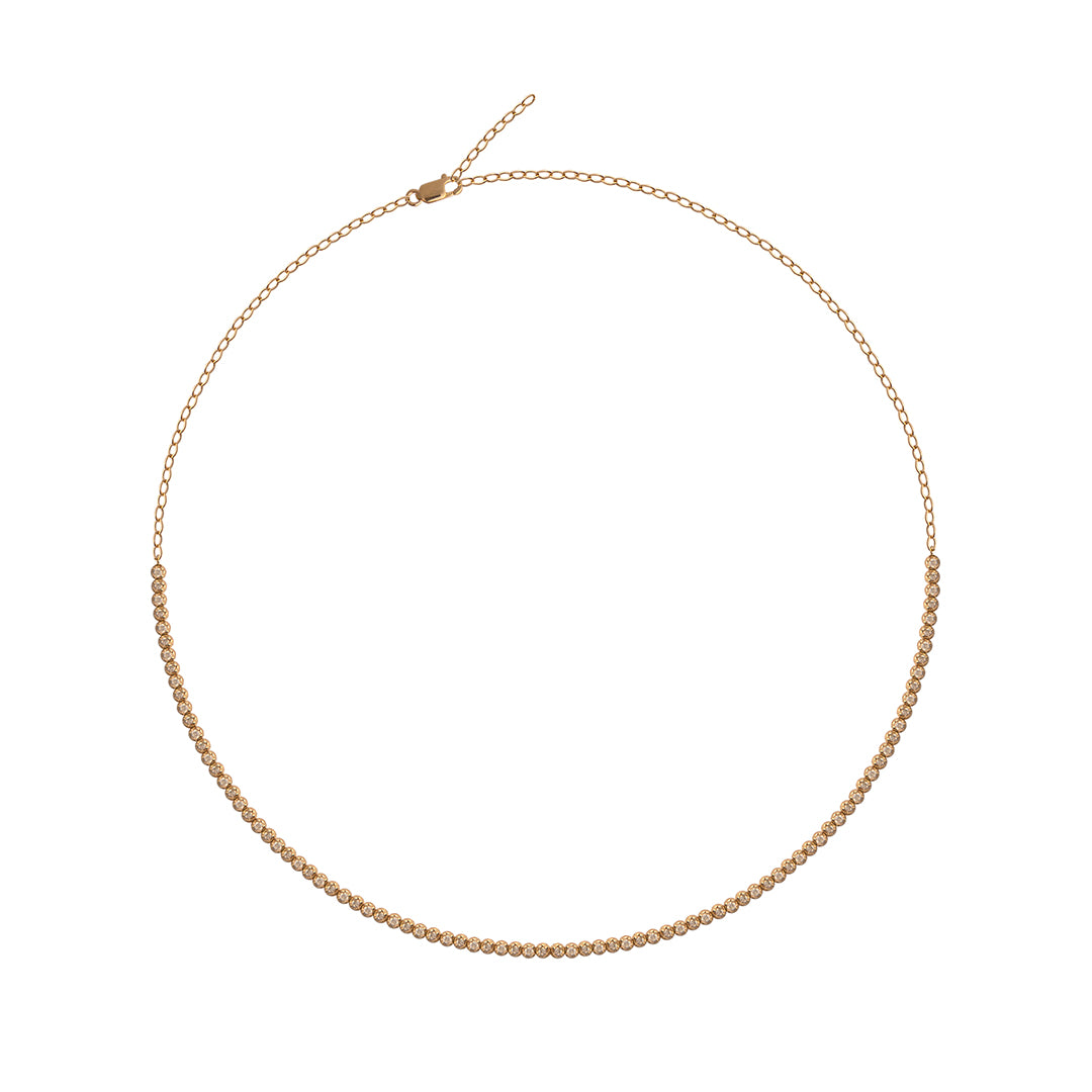A gold tennis necklace on a white background. 