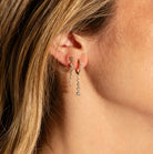 Close-up of a person wearing a pair of dangling diamond earrings.