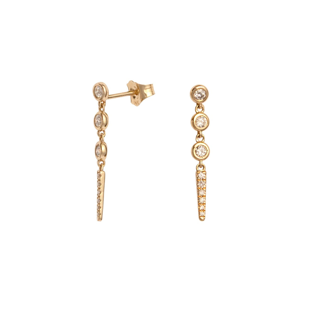 Gold earrings with bezel set diamonds diamonds on a white background.