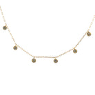 A delicate gold chain with bezel set diamonds suspended, on a white background. 