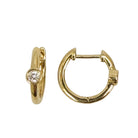 14k gold huggie earrings with a bezel set diamond on a white background.