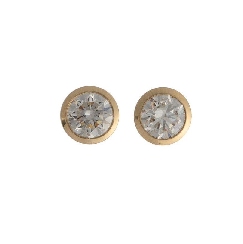 A pair of bezel set round lab-grown diamond studs in gold settings.