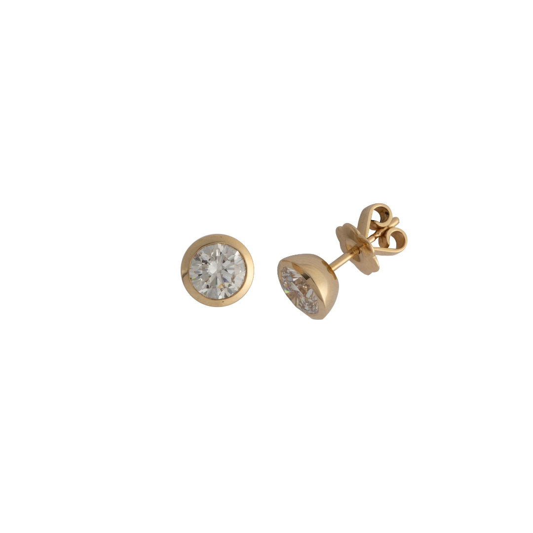 Gold stud earrings with bezel set lab grown diamonds on a white background.
