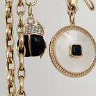 14k gold chains and two onyx and mother of pearl pendants with a white background.