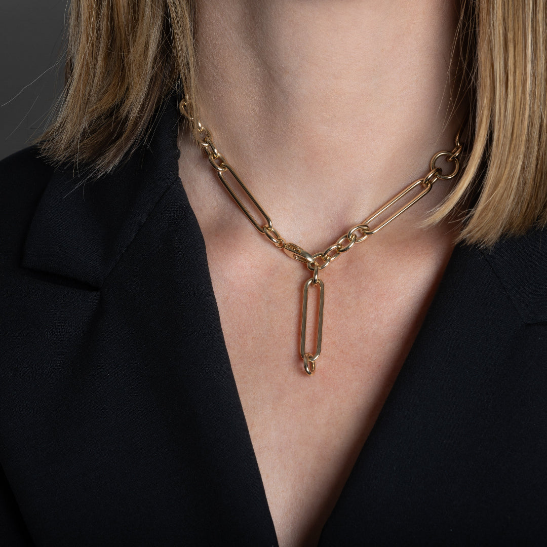 A person wearing a 14k gold chunky chain styled lariat style. 