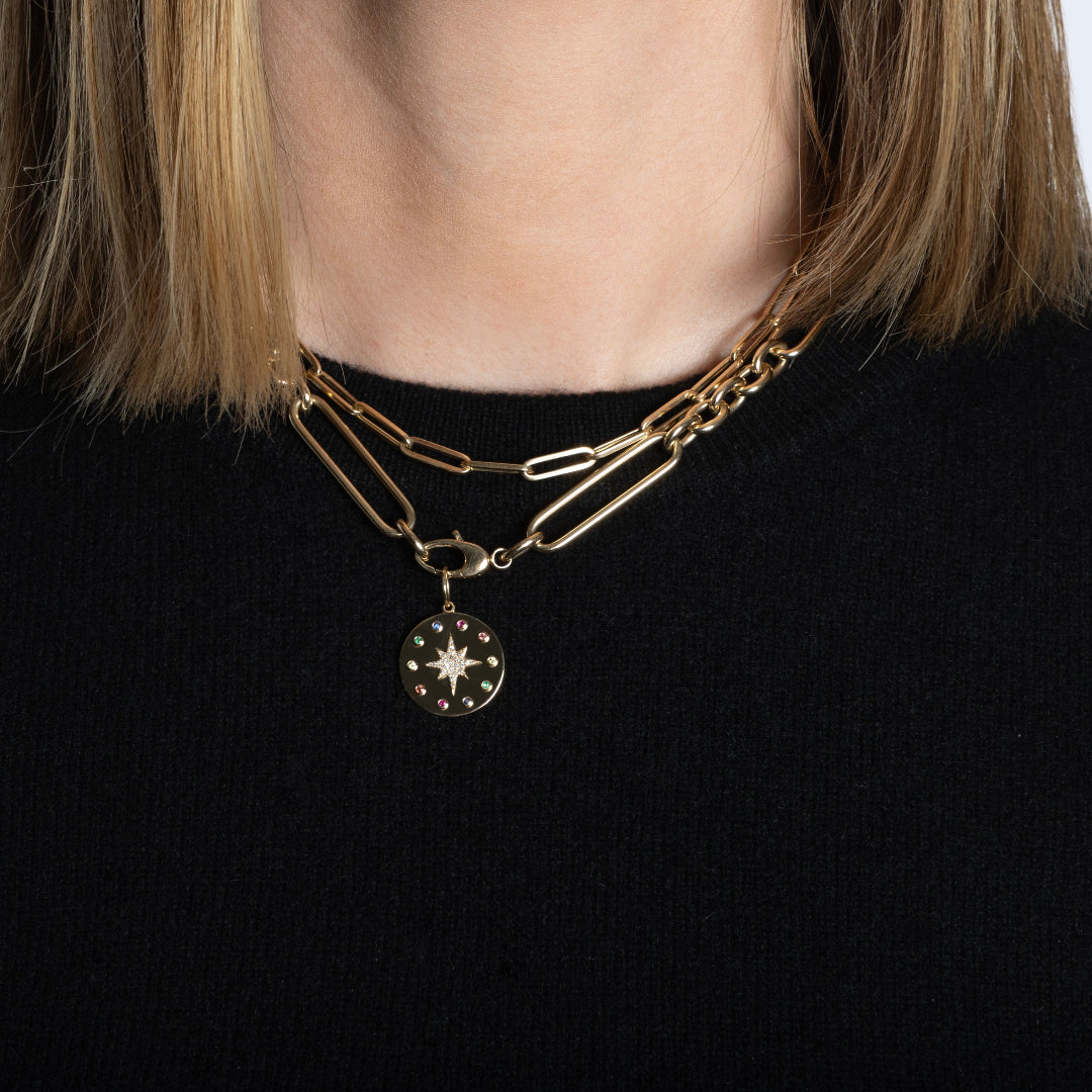 A person wearing two14k gold chains, one chunky mixed link with a pendant and one paperclip style. 