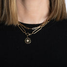 A person wearing two14k gold chains, one chunky mixed link with a pendant and one paperclip style. 