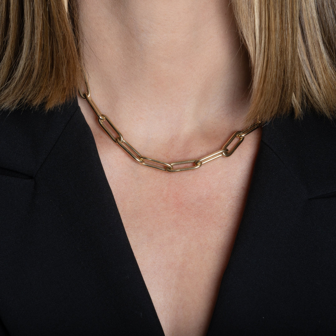 A person wearing a chunky paperclip chain necklace and a black blazer. 