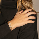 Close-up of a person wearing gold and white gold flexi bracelets and a ring and a black sweater