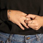 Close-up of hands with jewelry, wearing a black sweater and blue jeans.