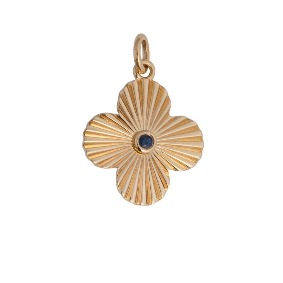 A gold pendant featuring a clover-shaped design with a blue sapphire center stone.