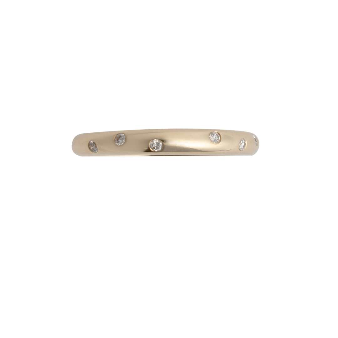 A thin band 14k gold with diamonds scattered throughout set on a white background. 