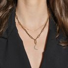 Gold chain necklace with a moon pendant worn by a person with a black blazer.