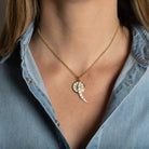 A person wearing a thin gold rolo chain with two white enamel pendants attached. 