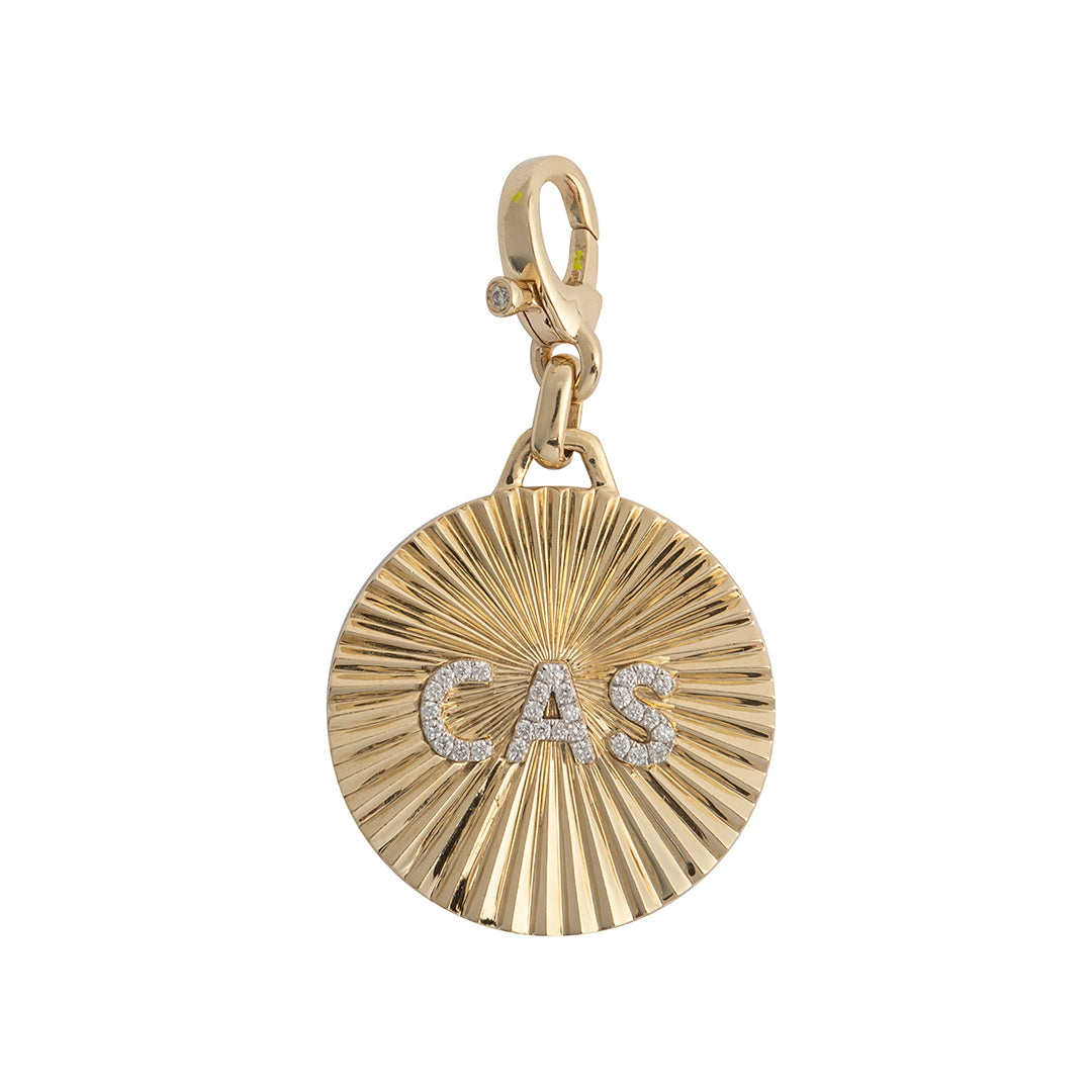A gold round starburst design custom initial pendant with diamond letters in the center, attached to a clasp.