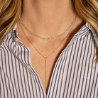 Gold necklaces worn by a person with a striped shirt.